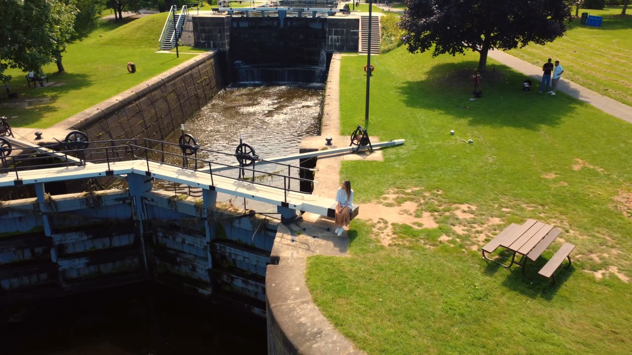 Performer seated beside canal locks during a music video shoot