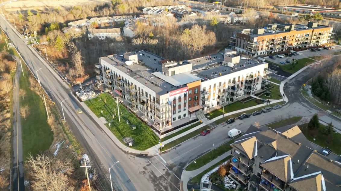 Aerial view of an apartment complex beside a tree-lined road